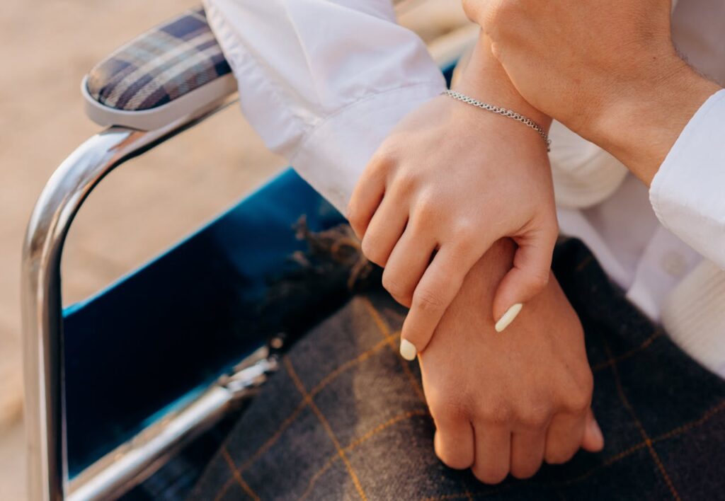 Romantic close-up of a couple holding hands in a wheelchair portraying love and support.